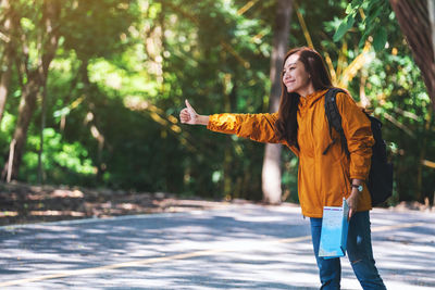 Young woman standing against trees