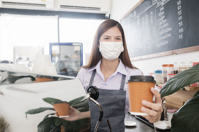 Portrait of barista holding coffee cup in cafe