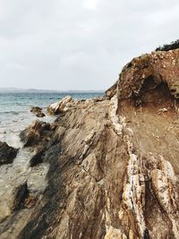 Rock formations on beach against sky