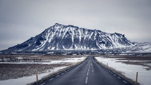 Road leading towards snowcapped mountain against sky