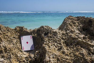 Heart shape on rock by sea against sky