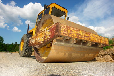Low angle view of bulldozer on road against sky