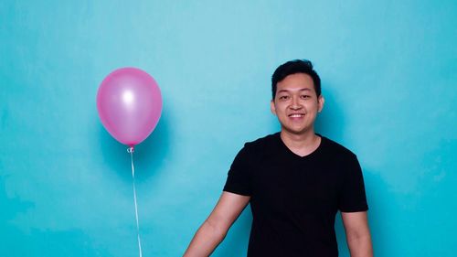 Portrait of smiling man standing against blue background