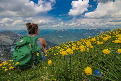 Rear view of woman with yellow flowers on field