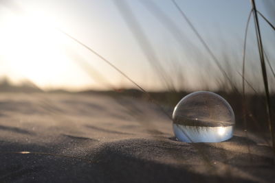 Close-up of crystal ball on sand at beach against sky