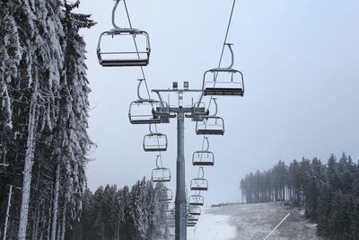 Overhead chairlift against sky during winter