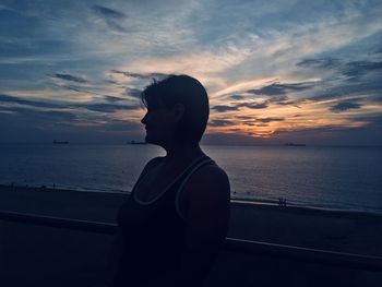 Man looking at sea against sky during sunset