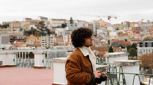 Smiling young woman with cityscape in background against sky