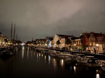Boats moored in harbor against buildings at night