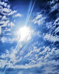 Low angle view of sunlight streaming through clouds