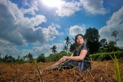 Young woman standing by agricultural field against sky