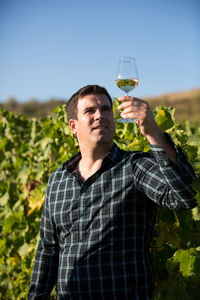 Portrait of young man drinking water against sky