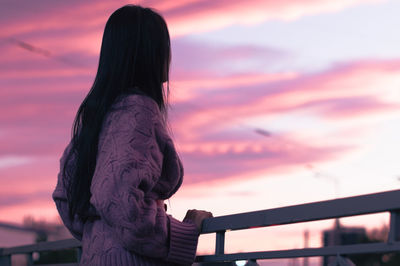 Rear view of woman standing against sky during sunset