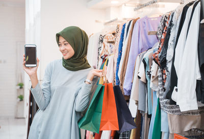 Young woman holding mobile phone in clothing store