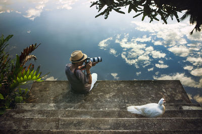 Man sitting by birds against sky