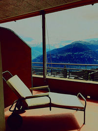 Empty chairs and tables against sky seen through window