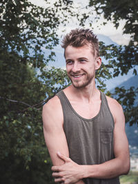 Portrait of young man standing against trees