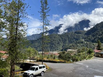 Road by trees and mountains against sky