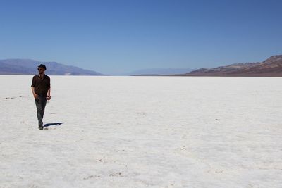 Full length of man walking on desert against clear sky