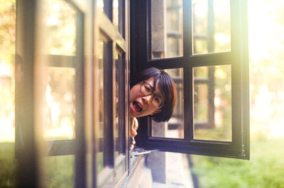 Young woman looking through window