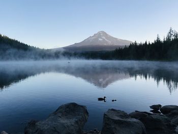 Scenic view of lake by mountains against clear sky