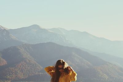 Young woman standing on mountain against sky