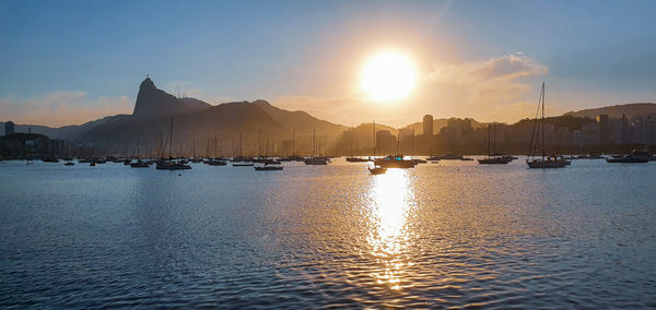 Sailboats in sea against sky during sunset