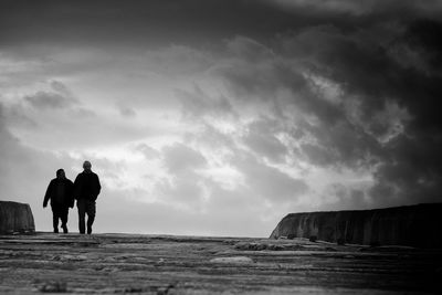 Rear view of silhouette man standing on sea shore against sky