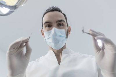 Close-up of doctor holding mask against white background