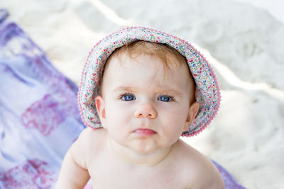 Potrait cute little baby girl with blue eyes in summer panama on background of white sand and plaid.