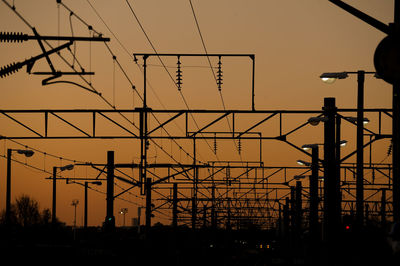 Low angle view of silhouette electricity pylon against sky during sunset