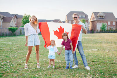 Happy canada day. caucasian family with kids boy and girl standing in park 
