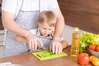 Father and son at home standing in the kitchen together, man smiling