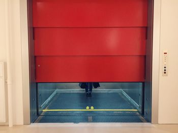 Woman walking on illuminated red door