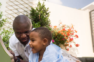 Father and son reading book together in the backyard