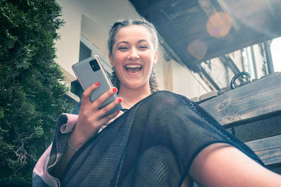 Young smiling woman using smartphone in cafe outdoor