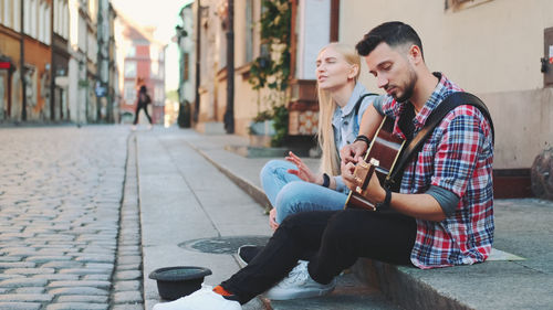 Young couple sitting on street in city