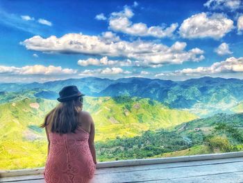 Rear view of woman standing on mountain against sky