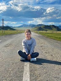 Portrait of girls sitting on road against sky