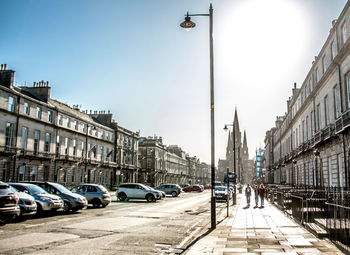 City street amidst buildings against sunny sky