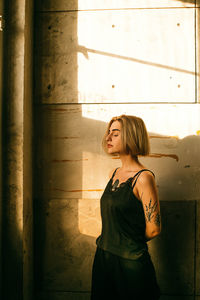 Full length of young woman standing against wall