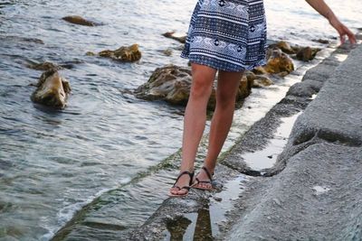 Low section of woman standing at beach