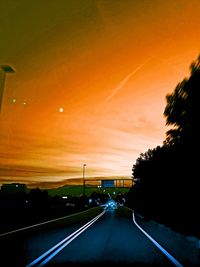 Road by trees against sky during sunset