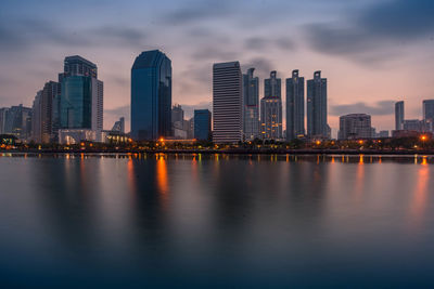 Sea by buildings against sky at dusk