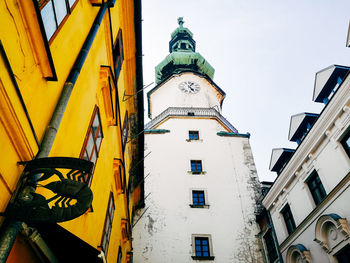 Low angle view of clock tower amidst buildings against sky