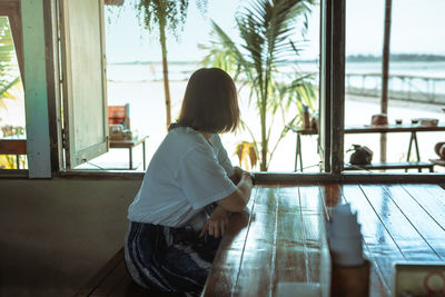 Rear view of woman standing by window