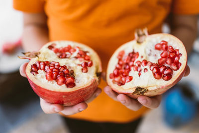 Midsection of person holding halved pomegranate