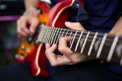 Midsection of man playing guitar