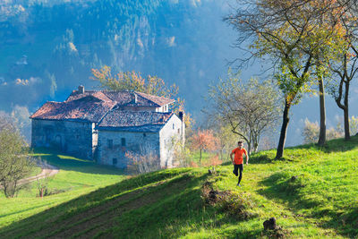 Rear view of man outside house on field