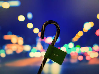 Close-up of padlocks on illuminated heart shape against blue sky